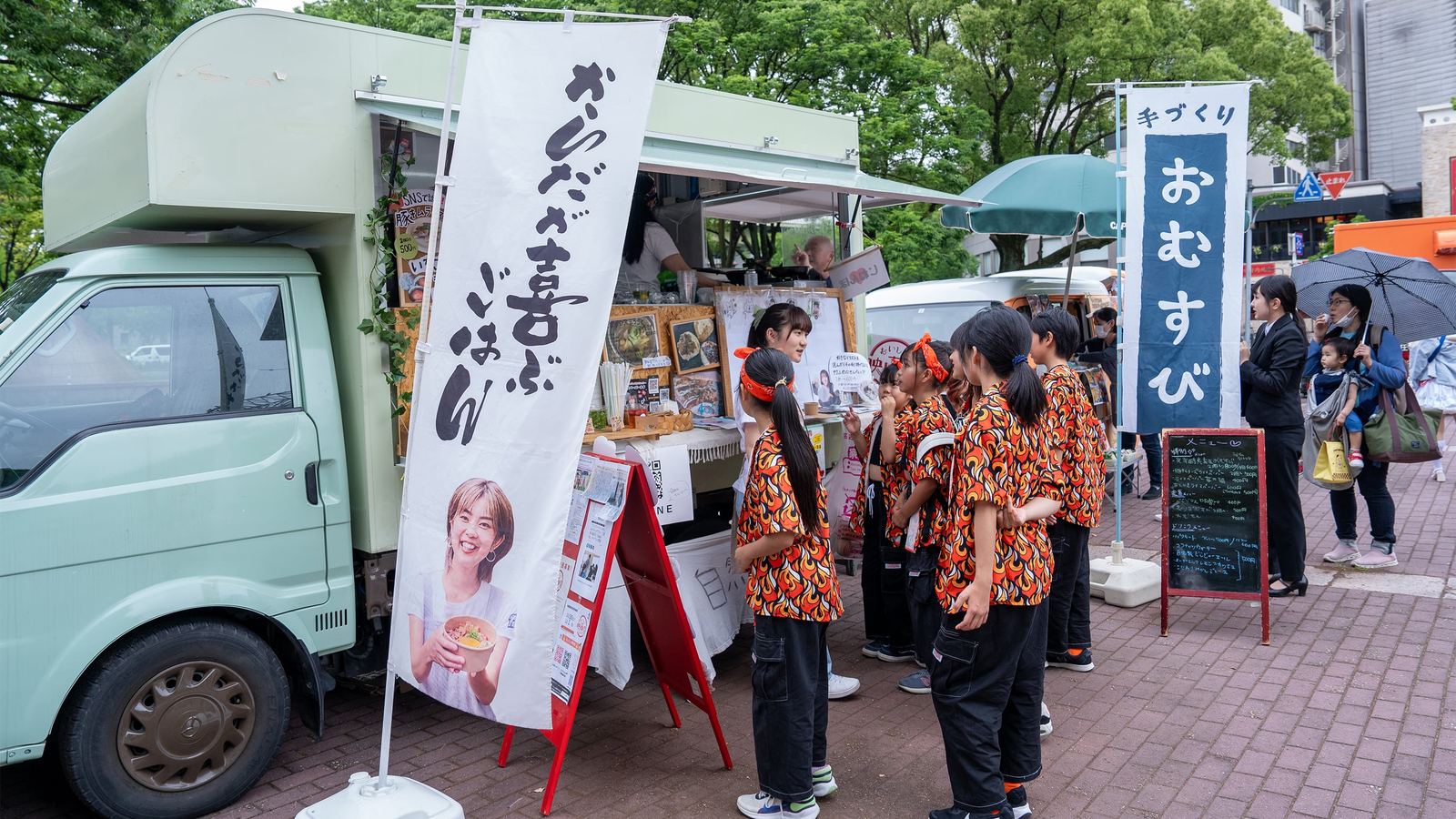 揃いのシャツを着た学生たちがキッチンカーの前に並ぶ様子